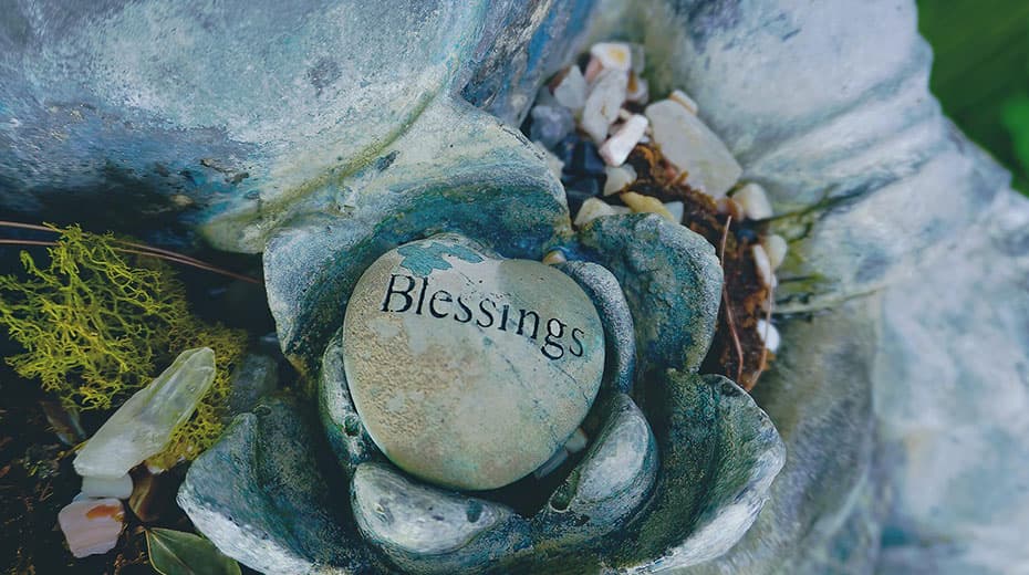 Stone inscribed with Blessings nestled in a decorative setting with small rocks and mosses.