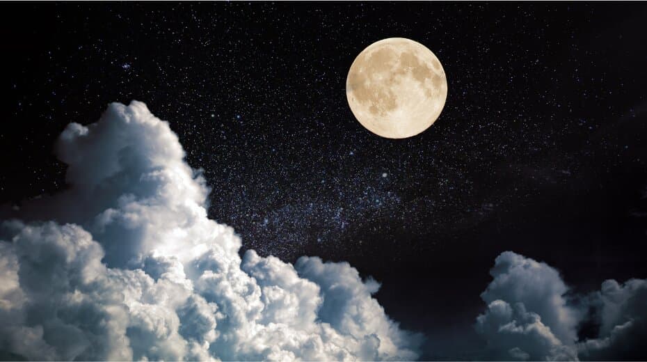Full moon illuminating a starry night sky above large billowing clouds.