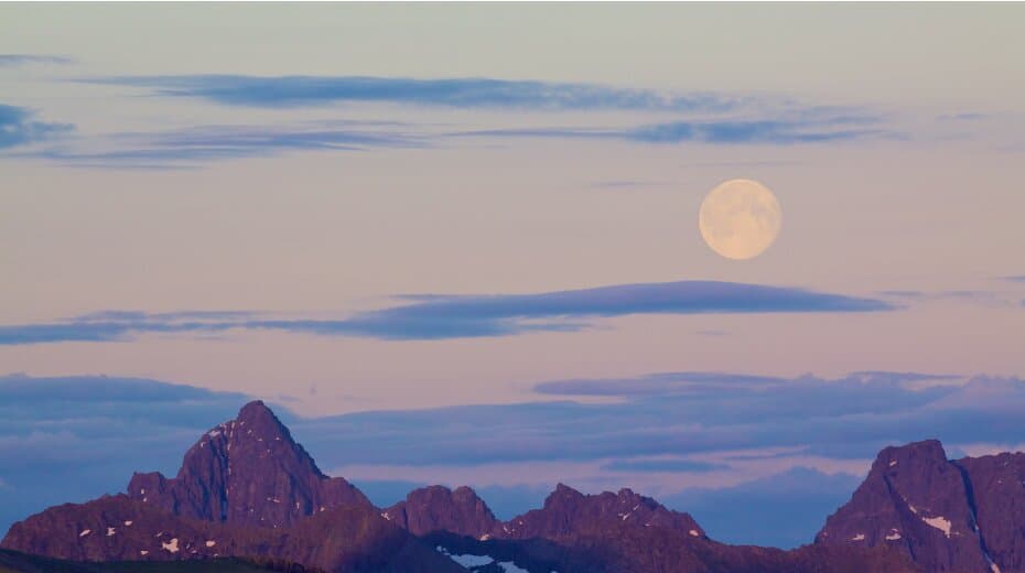 Full moon rises over a tranquil mountain range with a serene sky, symbolizing peace and balance in meditation and yoga practice.