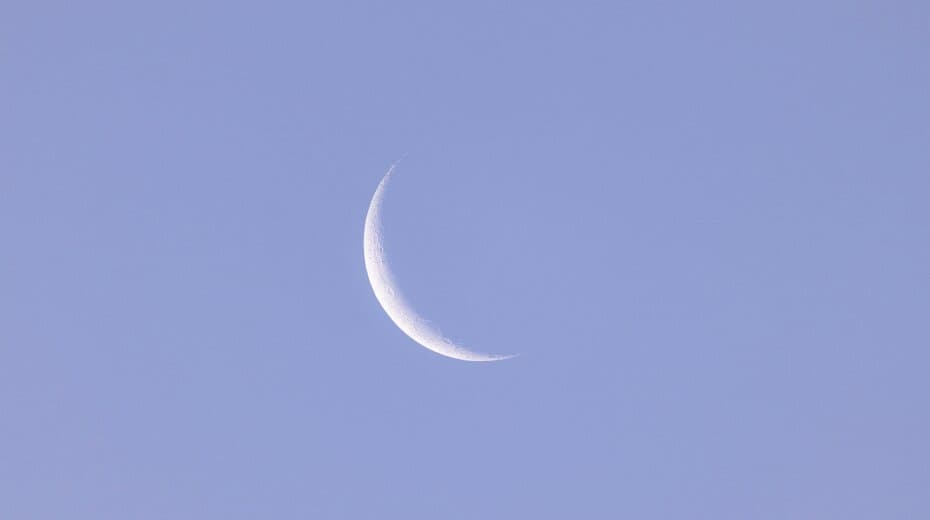 Crescent moon in a clear evening sky, symbolizing tranquility and new beginnings.