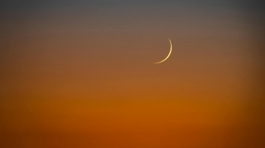 A crescent moon against a gradient sunset sky, symbolizing tranquility and new beginnings in yoga and meditation practices.