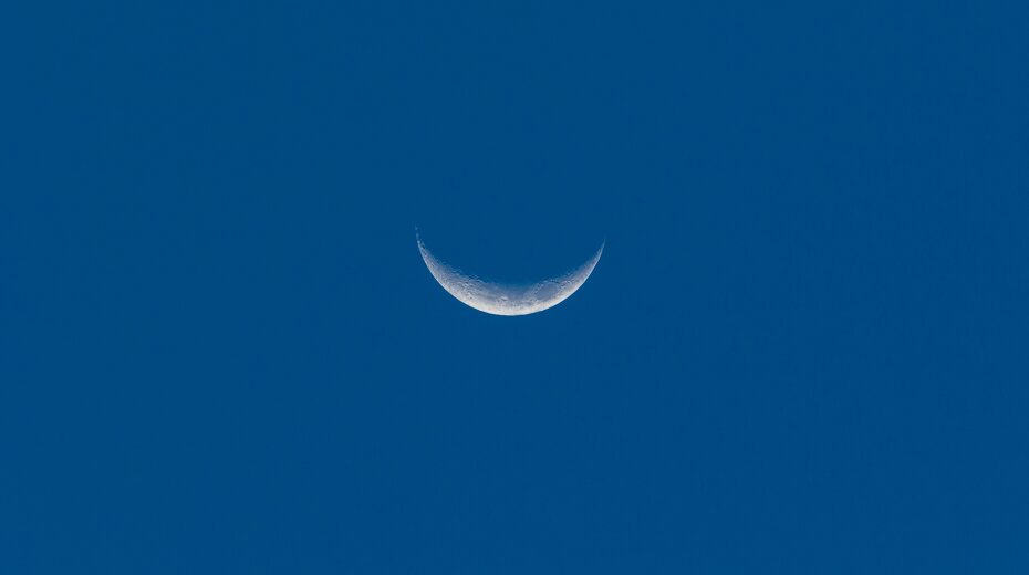Crescent moon in a clear blue sky.