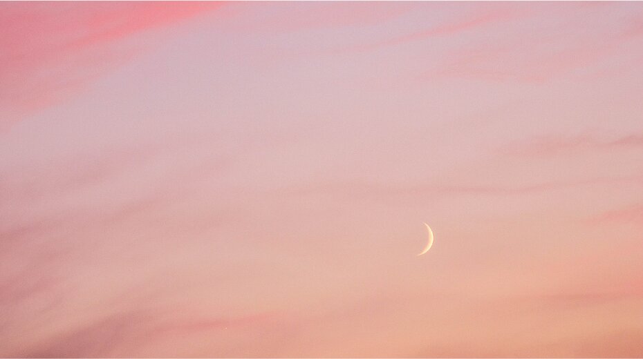 Crescent moon in a pink, cloudy sky, symbolizing a serene and spiritual ambiance perfect for meditation or yoga.