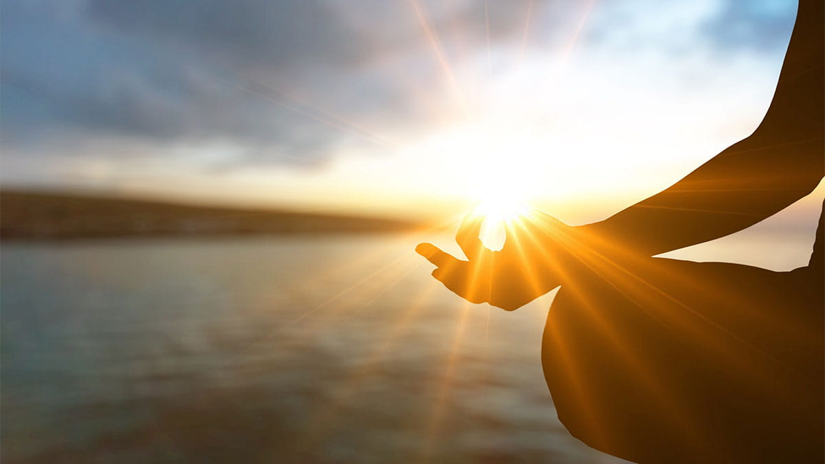 Woman meditating at sunrise with golden light symbolizing a spontaneous Kundalini awakening